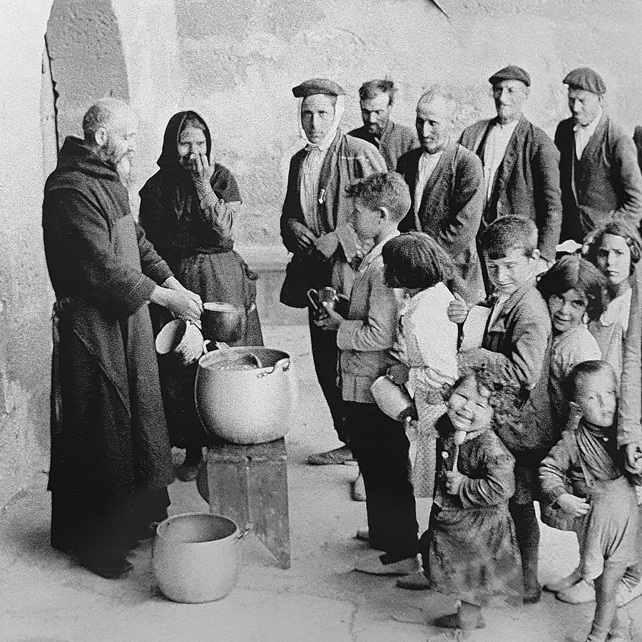 Un fraile reparte sopa a un grupo de pobres en el patio del monasterio de la Oliva